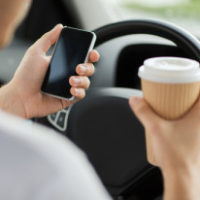 man looking at cell phone while driving