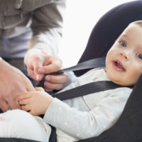 A dad strapping his son in car seat
