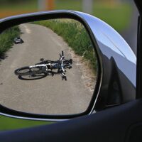 A crashed bicycle in a car’s side mirror, representing the need for a West Virginia bicycle accident attorney.
